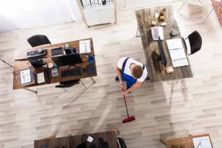 Gebäudereinigung Erhöhte Ansicht des männlichen Hausmeisters Reinigungsboden mit Besen am Arbeitsplatz