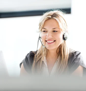 Kontakt lächelnde Kundendienstmitarbeiterin mit Headset am Computer