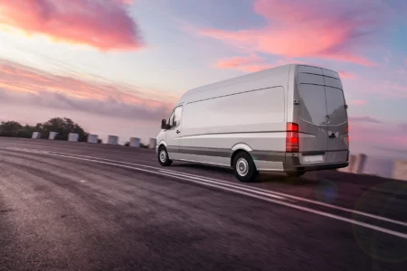 Transporter-Vermietung Grauer Lieferwagen der schnell auf der Autobahn fährt